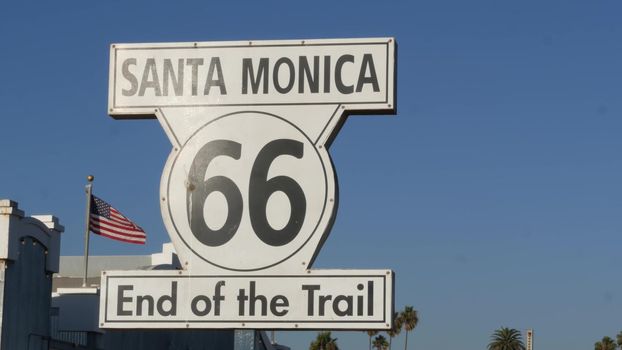 SANTA MONICA, LOS ANGELES, USA - 28 OCT 2019: Historic route 66, famous vintage california trip symbol. Pier of pacific ocean resort. Iconic retro road sign against the blue sky in amusement park.