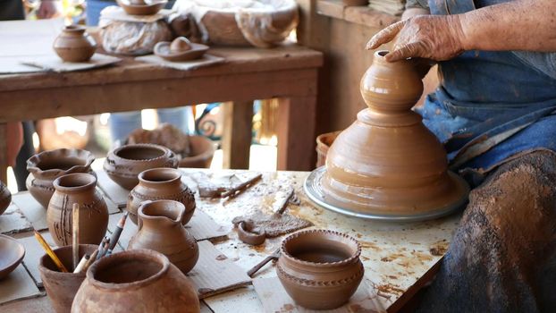 SAN DIEGO, CALIFORNIA USA - 5 JAN 2020: Potter working in mexican Oldtown, raw clay on pottery wheel. Man's hands, ceramist in process of modeling handcrafted clayware. Craftsman creating ceramic.