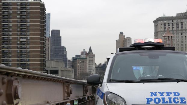 NEW YORK CITY, USA - 12 MAR 2020: Emergency siren glowing, 991 police patrol car on Brooklyn bridge. NYPD auto, symbol of crime prevention and safety in Manhattan. Metropolis security and protection.