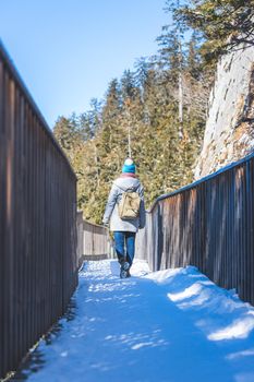 Young woman is walking on snowy wooden bridge