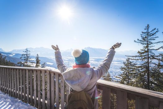 Back of young woman who is raising her hands on the mountain, outlook. Gaisberg, Austria