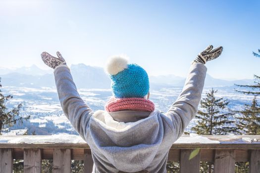 Back of young woman who is raising her hands on the mountain, outlook. Gaisberg, Austria