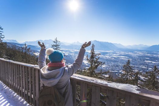 Back of young woman who is raising her hands on the mountain, outlook. Gaisberg, Austria