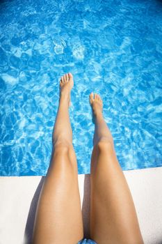 Slim legs of young woman in swimming pool. Summer time