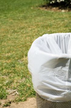 Trash bin in a park with white plastic bag. No people