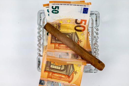 50 euro bills with cigar and ash holder on white background