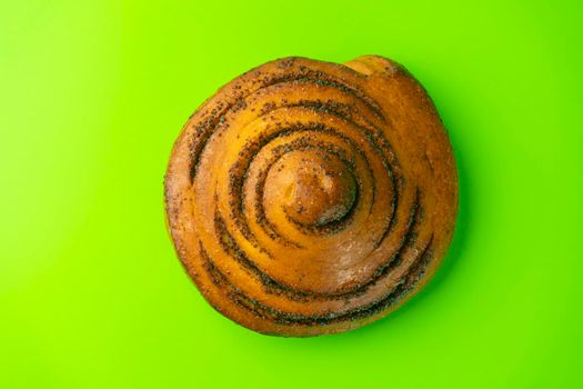 bun with poppy seeds on a green background close-up. isolate. High quality photo