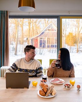 Young couple morning breakfast with laptop.Love,happiness,people and fun working from home concept. young couple mid age Asian and Causian man and woman working from home with laptop