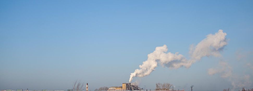 White thick smoke from the boiler room chimney. Smoke against the blue sky. Air pollution. Heating of the city. Industrial zone.