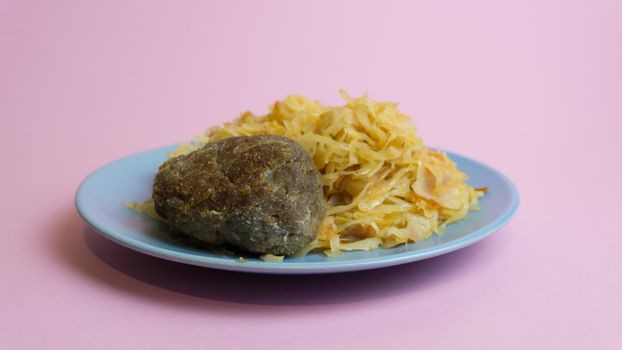 Stewed white cabbage with a cutlet steak on a plate. A dish of Russian cuisine. Garnish in the USSR.