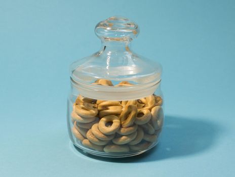 Yellow small bagels in a glass sealed container on a blue background.