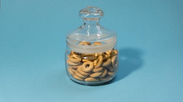 Yellow small bagels in a glass sealed container on a blue background.