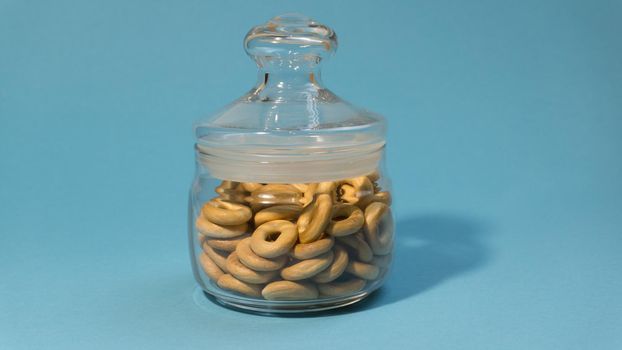 Yellow small bagels in a glass sealed container on a blue background.