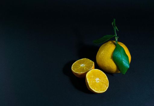 Tangerine cut with a green leaf on black background