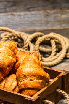 Wooden crate with delicious, fresh croissants isolated. French breakfast concept.