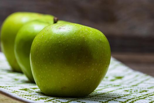 Detail on ripe green apples on wooden table.