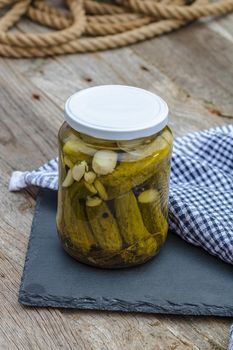 Close up of glass jar with pickles isolated. Preserved food concept, canned vegetables isolated in a rustic composition.