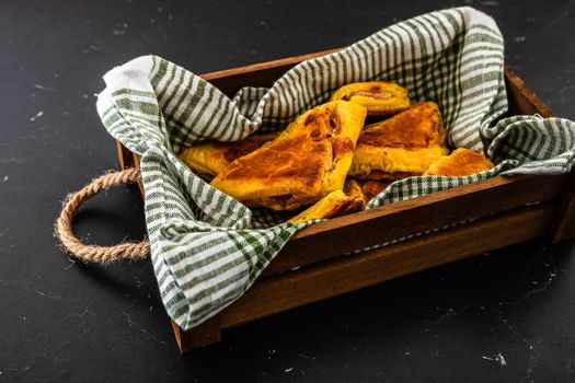 Freshly baked homemade ham and cheese puff pastry in a rustic crate.