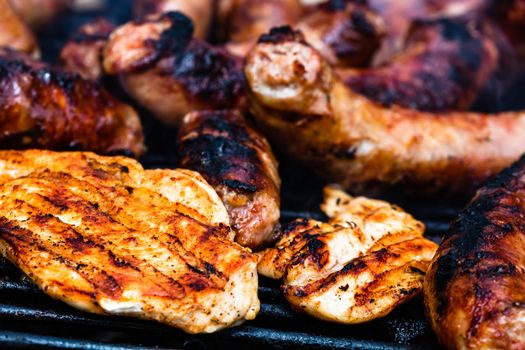 Close up on details of homemade chicken, pork steak and sausages on barbecue grill. Barbecue, grill and food concept.