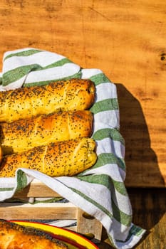 Sausages baked in dough sprinkled with salt and poppy seeds in a rustic basket. Sausages rolls, delicious homemade pastries in a rustic composition.