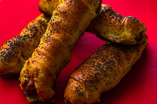 Close up of sausages baked in dough sprinkled with salt and poppy seeds. Sausages rolls, delicious homemade pastries isolated.
