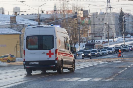 Tula, Russia - February 6, 2021: White ambulance minibus on winter wet street lane.