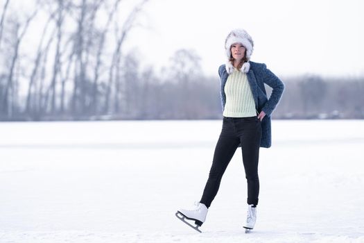 Gorgeous woman skating on frozen lake.