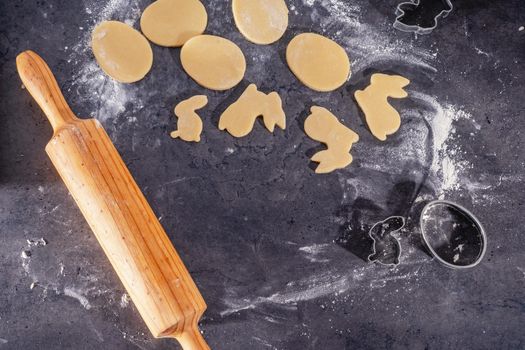 Rolling pin and kitchenware for making easter cookies on dark background.