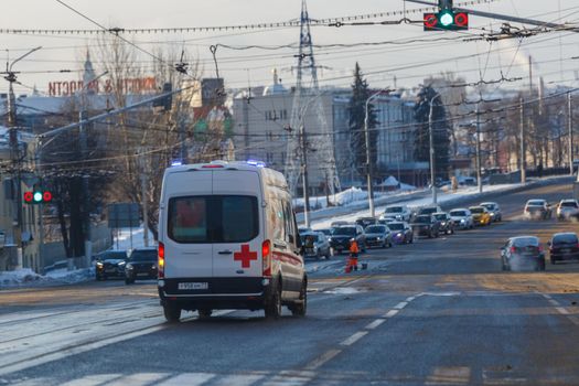 Tula, Russia - February 6, 2021: White ambulance minibus on winter wet street lane.