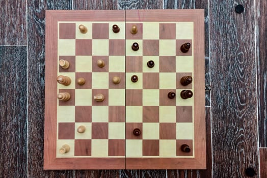 White and black chess pieces stand on board during a chess game. top view.