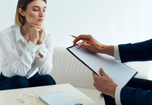 A man with documents and a woman on the couch at the table indoors staff psychologist reception doctor. High quality photo