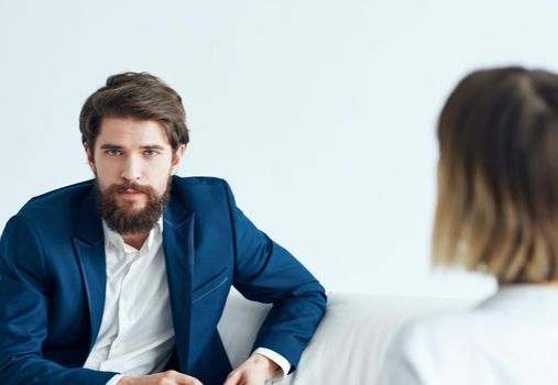 A man in a classic suit sits on the couch indoors with documents and a woman vacancy resume. High quality photo