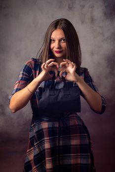 Portrait of a beautiful girl on a gray background, the girl holds a black handbag in front of her