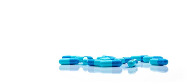 Blue antibiotic capsule pills spread on white background. Antibiotic drug resistance. Pharmaceutical industry. Healthcare and medicine concept. Health budget concept. Capsule manufacturing industry.