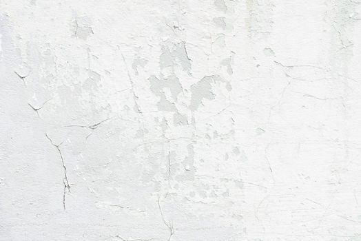 Outdoor concrete white wall with cracked and flaked surface close up