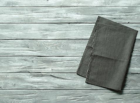 Gray wooden table with balck and white dark linen kitchen towel or textile napkin flat lay. Dark tablecloth on old gray wood tabletop. Copy space for text. Can use as mock up for design.