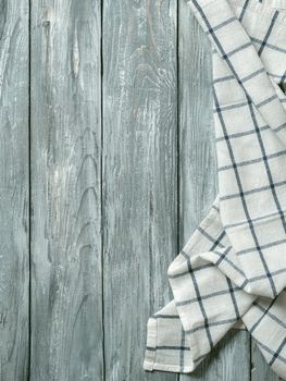 Gray wooden table with linen kitchen towel or textile napkin flat lay. Blue tablecloth on old gray wood tabletop. Copy space for text. Can use as mock up for design. Vertical.