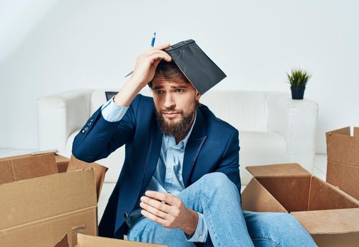 Business man with boxes sits on the office floor unpacking things. High quality photo