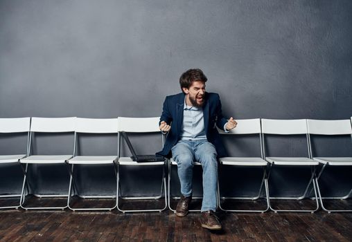 Business man in a suit sitting on a chair waiting laptop work office job interview. High quality photo