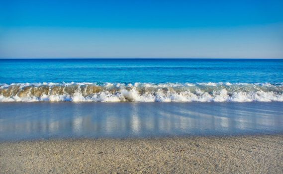 Seascape with clear blue sea, cloudless sky and white sandy beach