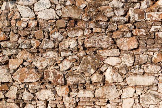 Old stone wall, painted in a faded white color and built with stones and mud