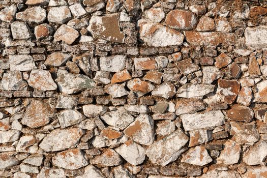 Old stone wall, painted in a faded white color and built with stones and mud