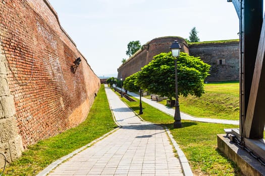 Green garden with clean grass, beautiful trees, alleys in a fortress yard. The fortification walls and promenades in Alba Iulia, Romania, 2021