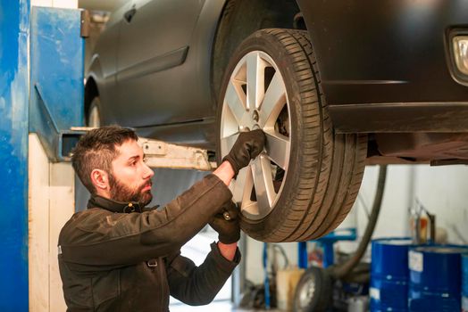 Mechanic performs tire change on the car in the workshop