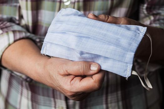 Person holding handmade hand-sewn face mask, shortage of medical protective masks due to global outbreak of COVID-19 corona virus disease, worldwide Coronavirus crisis, do it yourself PPE protection