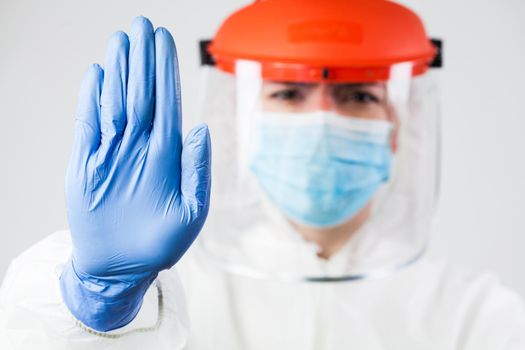 Lab scientist EMS ICU doctor wearing N95 biohazard PPE protective suit raised hand gesturing STOP Coronavirus 2019-ncov SARS-CoV-2 disease global pandemic outbreak,restrictive no entry quarantine zone