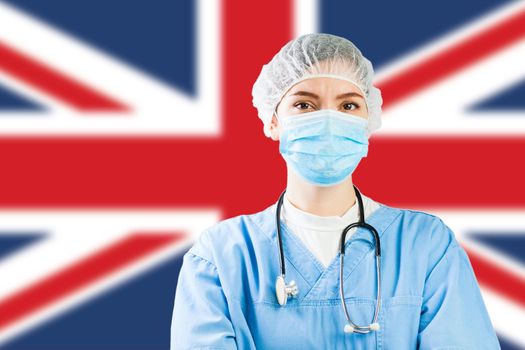 Portrait of UK NHS EMS caucasian hospital frontline ICU GP doctor in PPE Personal Protective Equipment,Great Britain flag background,COVID-19 virus disease crisis,Coronavirus global worldwide pandemic