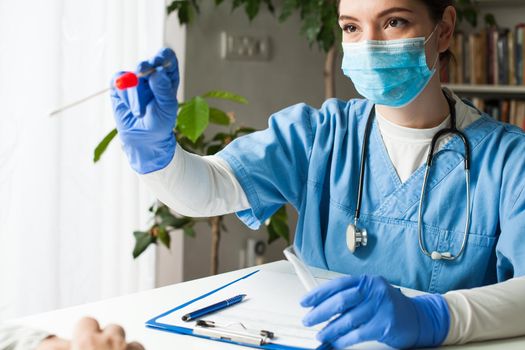 Female caucasian doctor holding a swab collection stick, nasal and oral specimen swabbing in doctor's office, patient PCR testing procedure appointment, Coronavirus COVID-19 global pandemic crisis