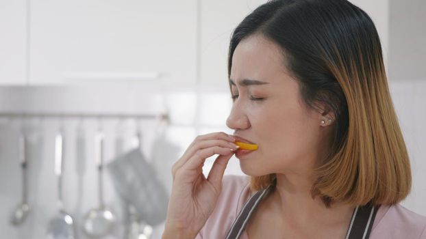 Portrait Asian young happy beautiful woman on kitchen she bite to eating fresh lemon kitchen. female emotion making a very sour expression. Healthy lifestyle concept. slow motion