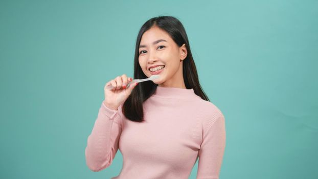 Asian young beautiful woman smile brushing teeth dancing enjoying music,  Female brush teeth singing song, dance and have fun isolated on blue background, lifestyle dental hygiene and health concept